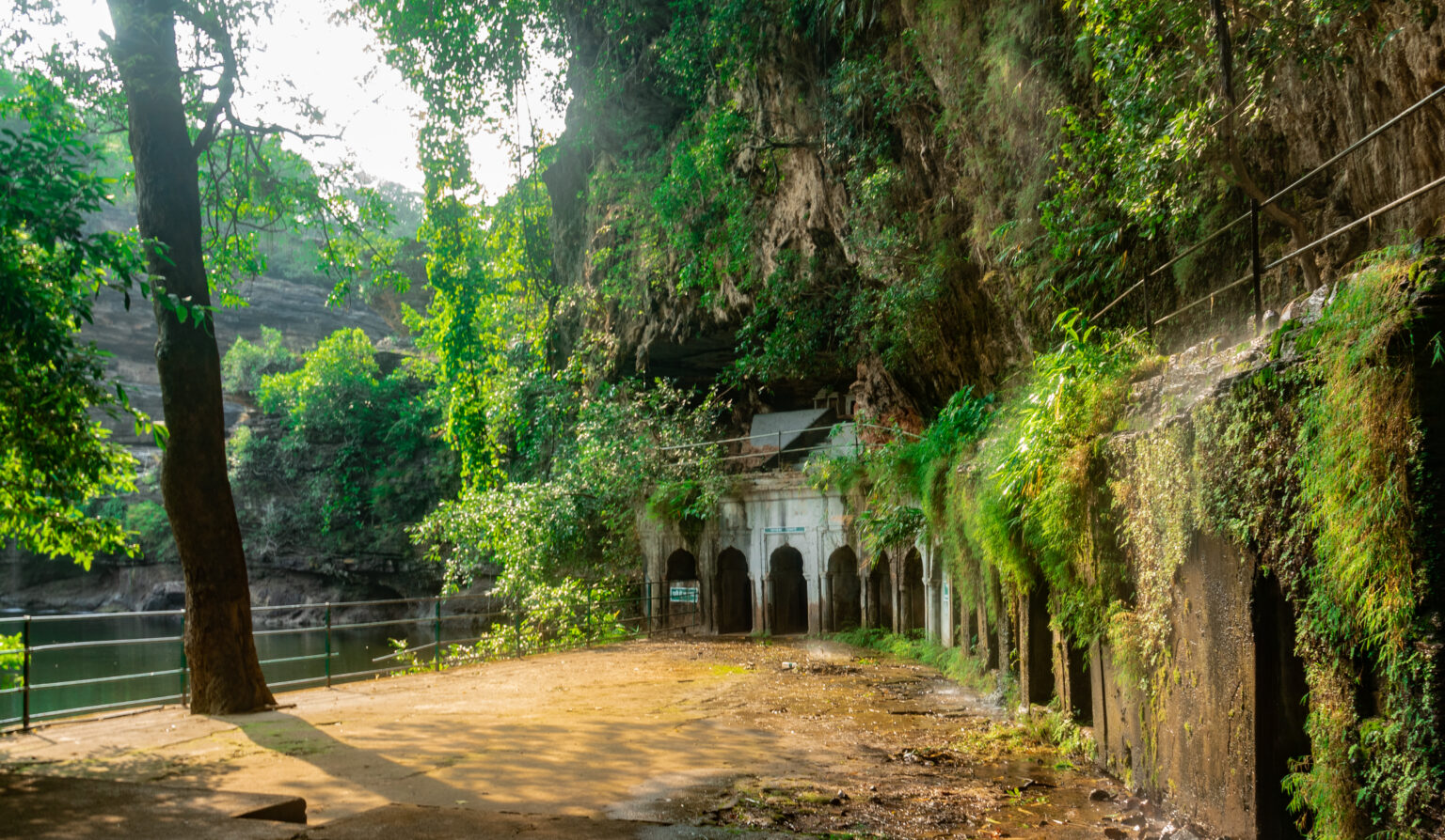 Pandav Falls cascading 30 meters into a heart-shaped pool in the forest near Panna with caves in the background